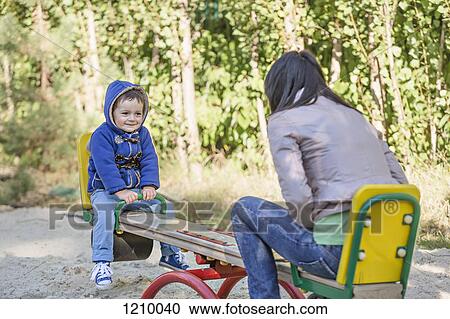 Stock Image - A young mother and her young son on a seesaw at a playground. Fotosearch