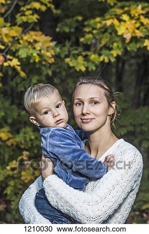 A young mother holding her son in an autumn setting View Large Photo Image Stock Image - A young mother holding her son in an autumn setting. Fotosearch