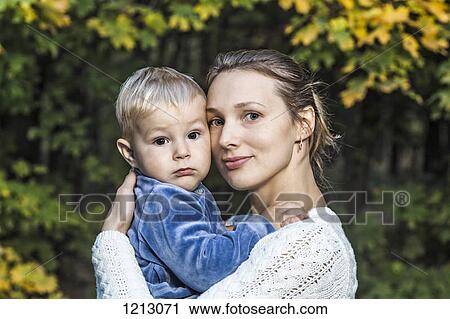 A young mother holding her son in an autumn setting View Large Photo Image Stock Image - A young mother holding her son in an autumn setting. Fotosearch