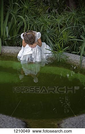 A young sad girl resting her head on her hands while sitting by a pond View Large Photo Image Stock Photo - A young sad girl resting her head on her hands while sitting by a pond. Fotosearch