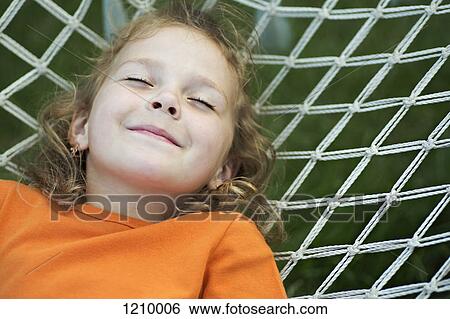 A young smiling girl lying on a hammock with her eyes closed View Large Photo Image Stock Photograph - A young smiling girl lying on a hammock with her eyes closed. Fotosearch