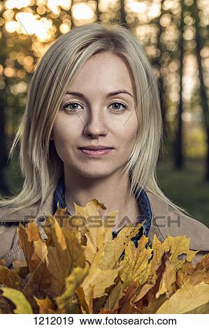 A young woman holding a bunch of autumn leaves in nature View Large Photo Image Stock Photo - A young woman holding a bunch of autumn leaves in nature. Fotosearch