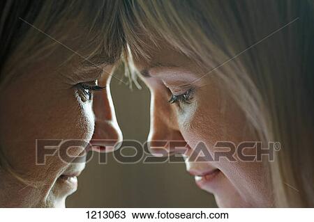 Stock Image - An adult woman touching foreheads with her mother, close-up. Fotosearch
