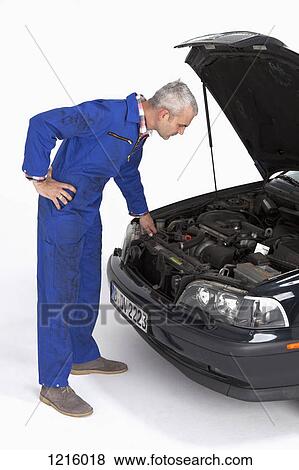 Stock Photo - An auto mechanic looking under the hood of a car thoughtfully. Fotosearch