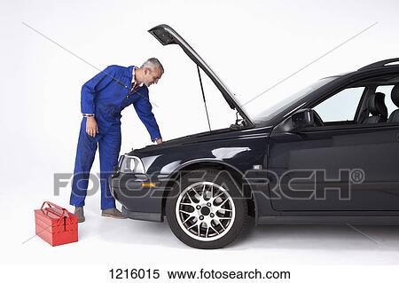 Stock Photography - An auto mechanic looking under the hood of a car. Fotosearch