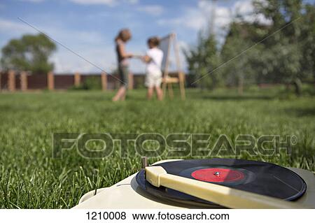 Stock Photo - An old-fashioned record player on a lawn, children in background. Fotosearch