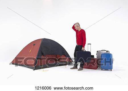 An unhappy man with loads of luggage looking at a tent with uncertainty View Large Photo Image Stock Photograph - An unhappy man with loads of luggage looking at a tent with uncertainty. Fotosearch