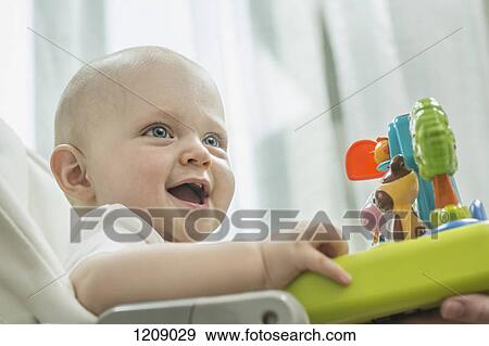 Stock Photo - Baby in high chair with toy animals. Fotosearch