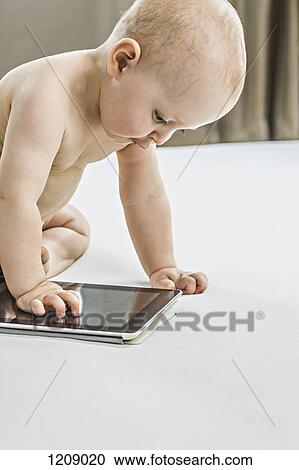Baby looking at digital tablet on bed View Large Photo Image Stock Image - Baby looking at digital tablet on bed. Fotosearch