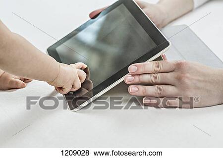 Baby pointing at Digital tablet held by his mother View Large Photo Image Stock Photo - Baby pointing at Digital tablet held by his mother. Fotosearch