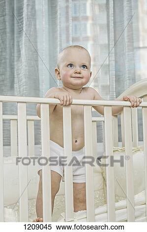 Baby standing up in cot View Large Photo Image Stock Photography - Baby standing up in cot. Fotosearch