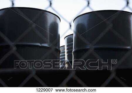 Black barrels behind wire mesh fence View Large Photo Image Stock Photo - Black barrels behind wire mesh fence. Fotosearch