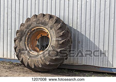 Construction vehicle wheel leaning against industrial building View Large Photo Image Stock Photo - Construction vehicle wheel leaning against industrial building. Fotosearch