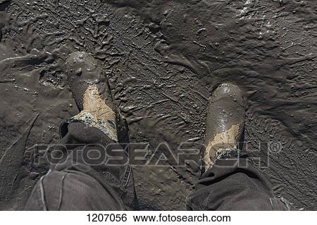 Stock Photograph - Construction worker's feet in mud of tyre track. Fotosearch