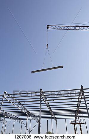 Crane lowering steel beam towards construction frame View Large Photo Image Stock Photograph - Crane lowering steel beam towards construction frame. Fotosearch
