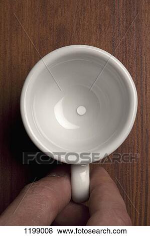 Stock Photo - Detail of a man holding a ceramic cup containing a tablet. Fotosearch