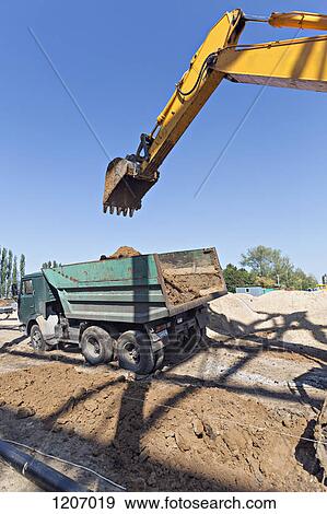 Digger loading soil onto dumper truck View Large Photo Image Stock Photo - Digger loading soil onto dumper truck. Fotosearch