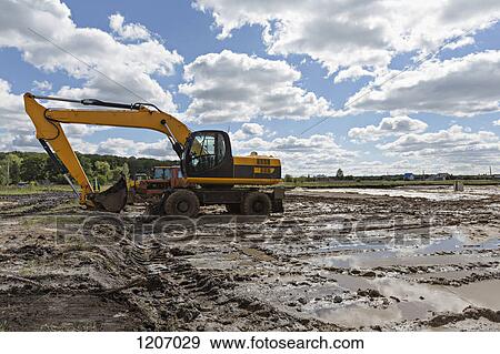 Stock Photo - Digger on muddy construction site. Fotosearch