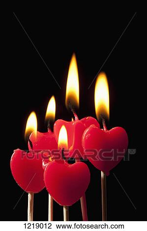 Stock Image - Five lit heart shaped candles on sticks arranged in a group. Fotosearch