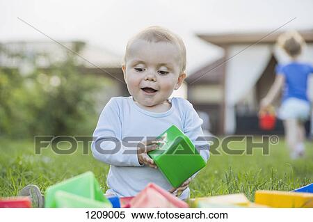 Stock Photography - Happy baby in the garden playing with building blocks. Fotosearch