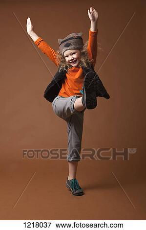 Stock Photo - Happy girl with arms raised and on one leg. Fotosearch