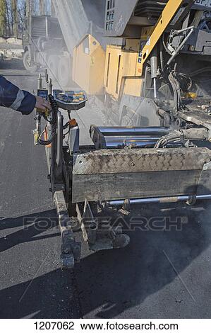 Manual worker controlling large road surfacing machine being trailed by articulated lorry View Large Photo Image Stock Image - Manual worker controlling large road surfacing machine being trailed by articulated lorry. Fotosearch