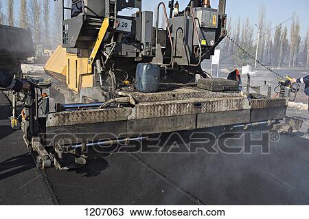 Manual workers controlling large road surfacing machine being trailed by articulated lorry View Large Photo Image Stock Image - Manual workers controlling large road surfacing machine being trailed by articulated lorry. Fotosearch
