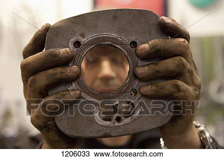 Stock Image - Mechanic showing motorcycle cylinder. Fotosearch