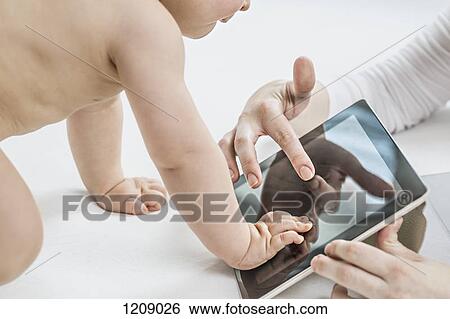 Mother showing her son a digital tablet View Large Photo Image Stock Photograph - Mother showing her son a digital tablet. Fotosearch