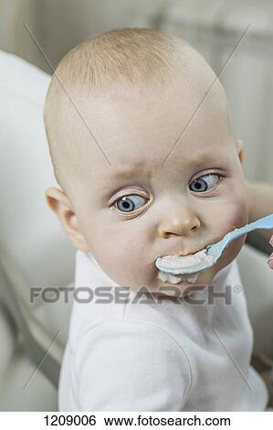 Stock Photograph - Mother spoon feeding her son. Fotosearch
