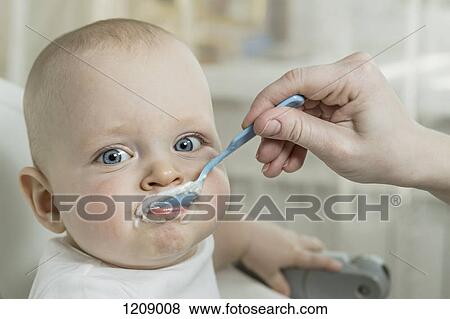 Stock Photo - Mother spoon feeding son. Fotosearch