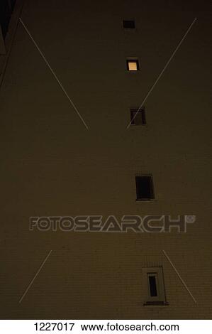 Stock Photo - One illuminated window in an otherwise darkened building, low angle view. Fotosearch