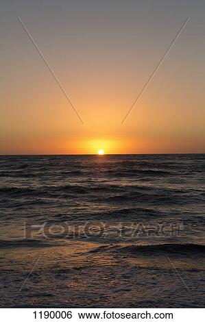 Stock Photograph - Sun setting on the sea. Fotosearch