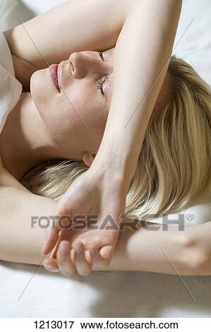Stock Photo - The sun shining on a woman lying down with eyes closed. Fotosearch
