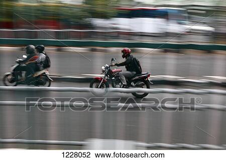 Stock Image - Three motorcycle rides on the streets of Jakarta, Indonesia. Fotosearch