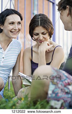 Three woman enjoying each others company while sitting in a park View Large Photo Image Stock Image - Three woman enjoying each others company while sitting in a park. Fotosearch