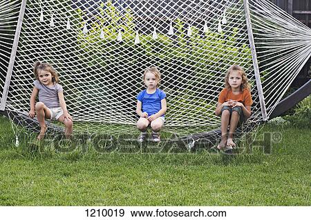Three young girls sitting on a hammock View Large Photo Image Stock Photo - Three young girls sitting on a hammock. Fotosearch
