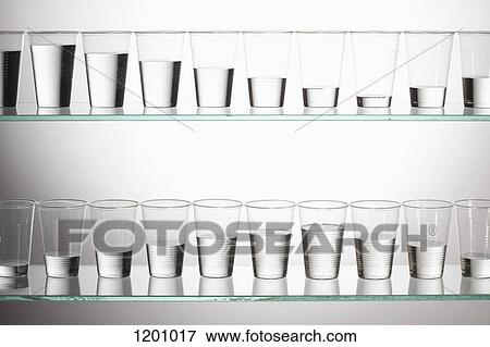 Two shelves with glasses of water filled with varying amounts of water View Large Photo Image Stock Photo - Two shelves with glasses of water filled with varying amounts of water. Fotosearch
