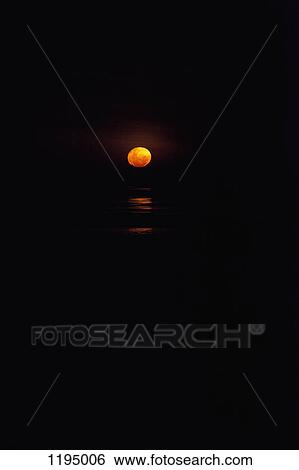Stock Photograph - View of the setting sun over water. Fotosearch