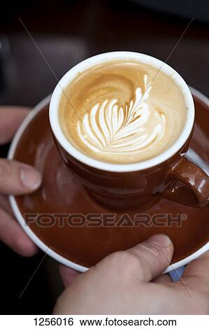 A barista serving a cappuccino with a floral pattern in the milk froth View Large Photo Image Stock Photograph - A barista serving a cappuccino with a floral pattern in the milk froth. Fotosearch