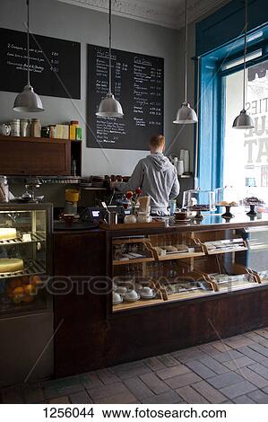 Picture - A barista working at an espresso maker in a cafe, rear view. Fotosearch