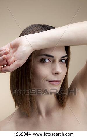 A beautiful young woman with her forearm resting on her forehead looking coyly into the camera View Large Photo Image Picture - A beautiful young woman with her forearm resting on her forehead looking coyly into the camera. Fotosearch