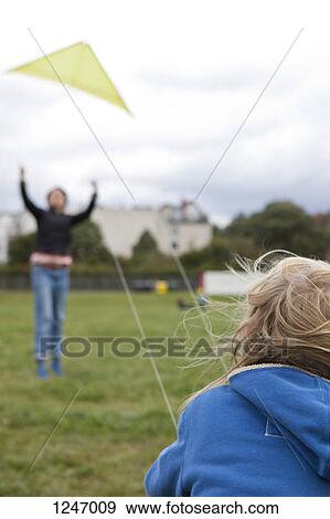 A boy flying a kite with the help of his mother in the background, focus on boy View Large Photo Image Stock Photo - A boy flying a kite with the help of his mother in the background, focus on boy. Fotosearch