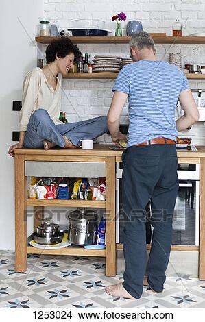 A cheerful mixed age couple preparing food in their kitchen View Large Photo Image Picture - A cheerful mixed age couple preparing food in their kitchen. Fotosearch