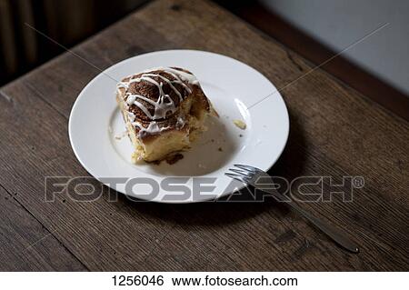 A cinnamon roll on a plate with a bite missing on a table in a coffee shop View Large Photo Image Stock Photograph - A cinnamon roll on a plate with a bite missing on a table in a coffee shop. Fotosearch