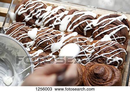 A coffee shop employee putting icing on a cinnamon rolls View Large Photo Image Stock Image - A coffee shop employee putting icing on a cinnamon rolls. Fotosearch