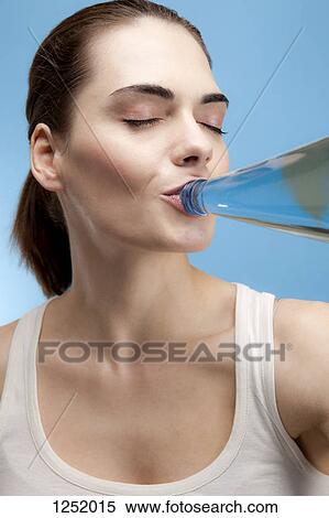 A content young woman drinking water from a glass water bottle View Large Photo Image Stock Photography - A content young woman drinking water from a glass water bottle. Fotosearch