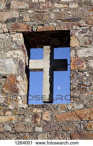 Stock Image - A cross in an open window of the stone wall of a church. Fotosearch