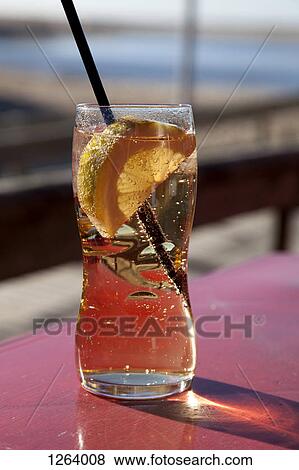 A glass of carbonated liquid with a slice of lemon and straw on a sunny day View Large Photo Image Stock Photo - A glass of carbonated liquid with a slice of lemon and straw on a sunny day. Fotosearch