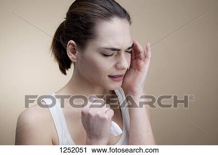 A grimacing young woman holding a tissue with her hand to her temple View Large Photo Image Stock Image - A grimacing young woman holding a tissue with her hand to her temple. Fotosearch